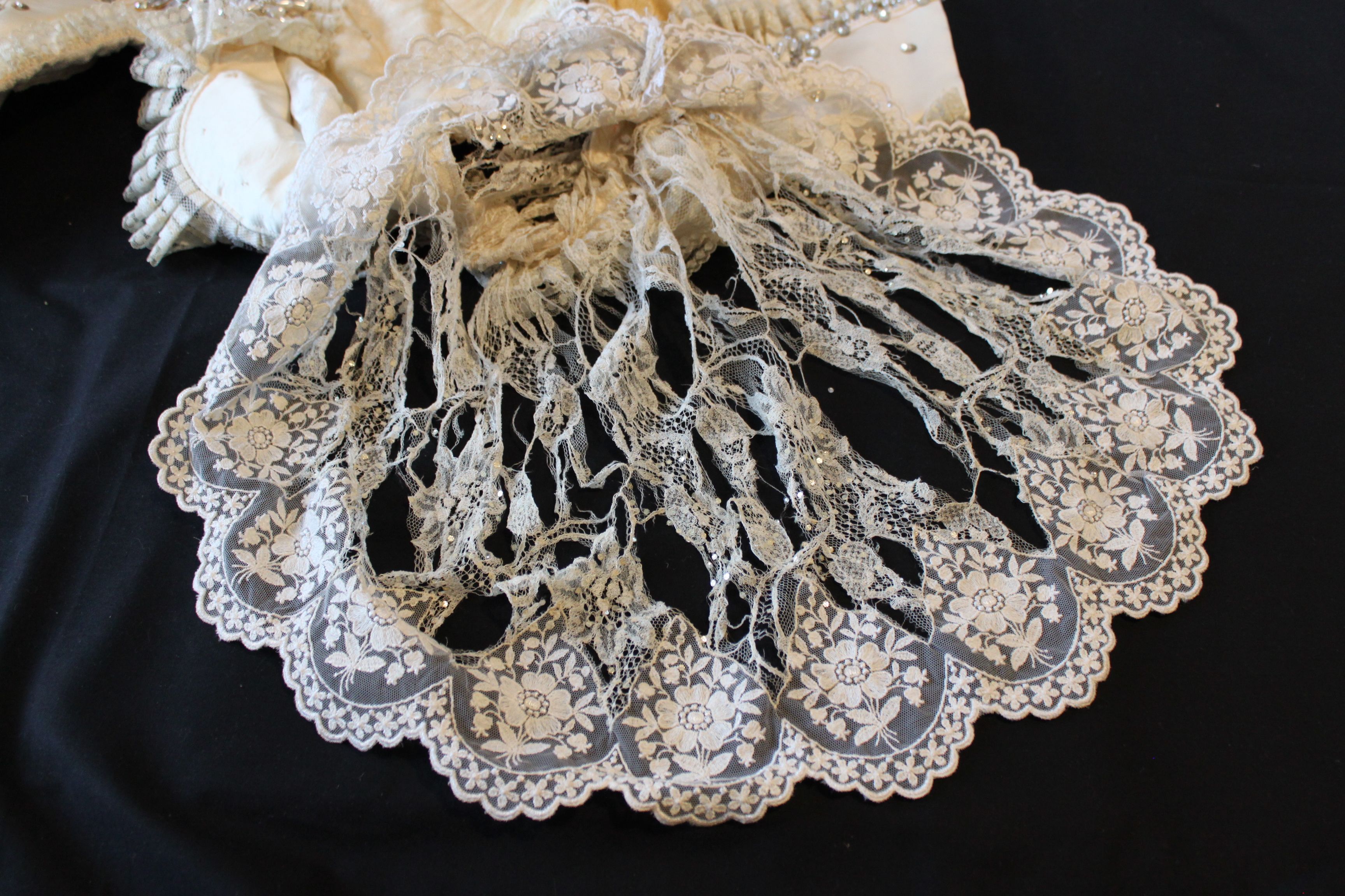 A lace frill, with tears and holes in the openwork lace pattern