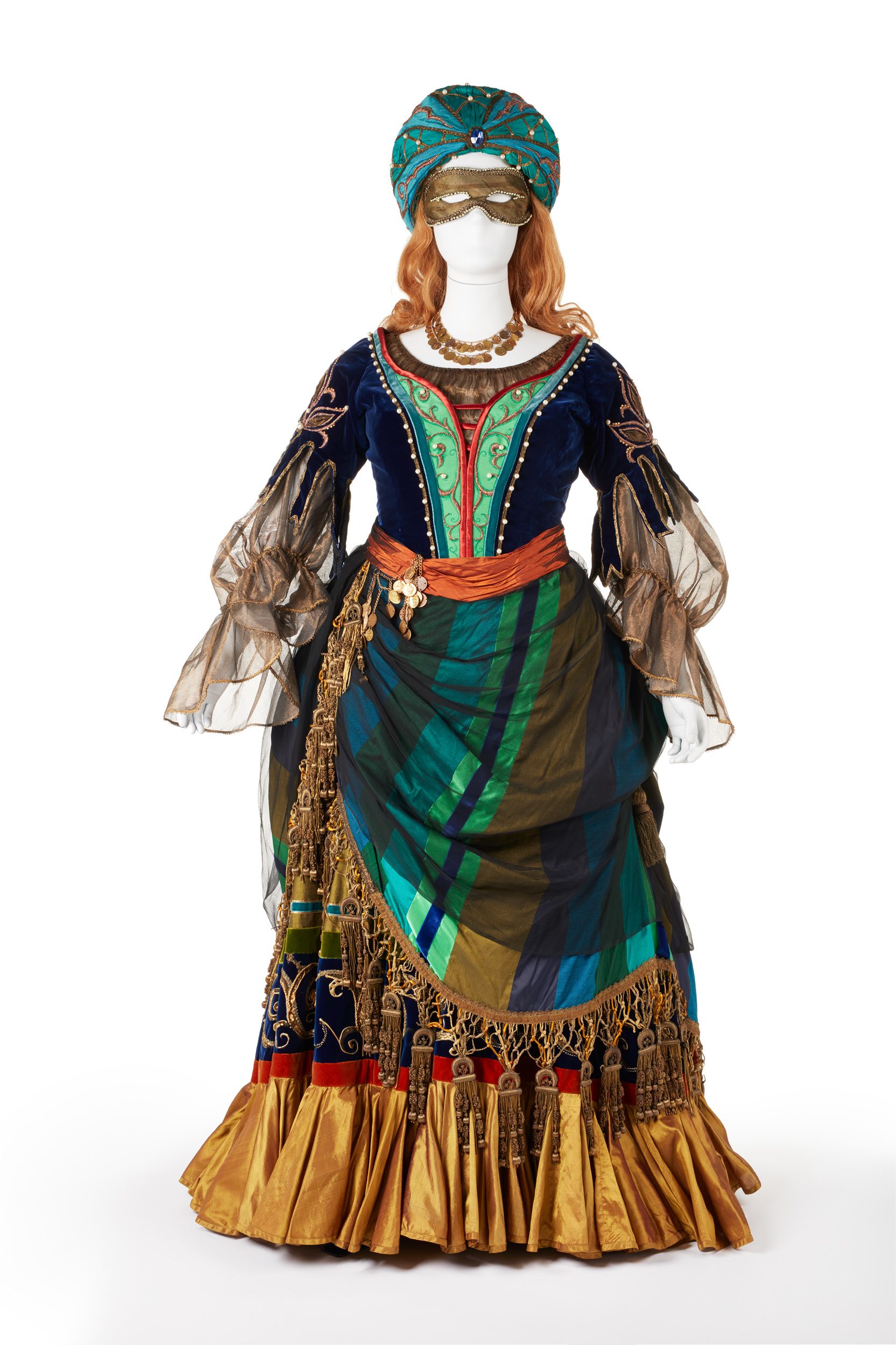 A blue and green dress with gold fringing and sleeves, and a turban and eyemask