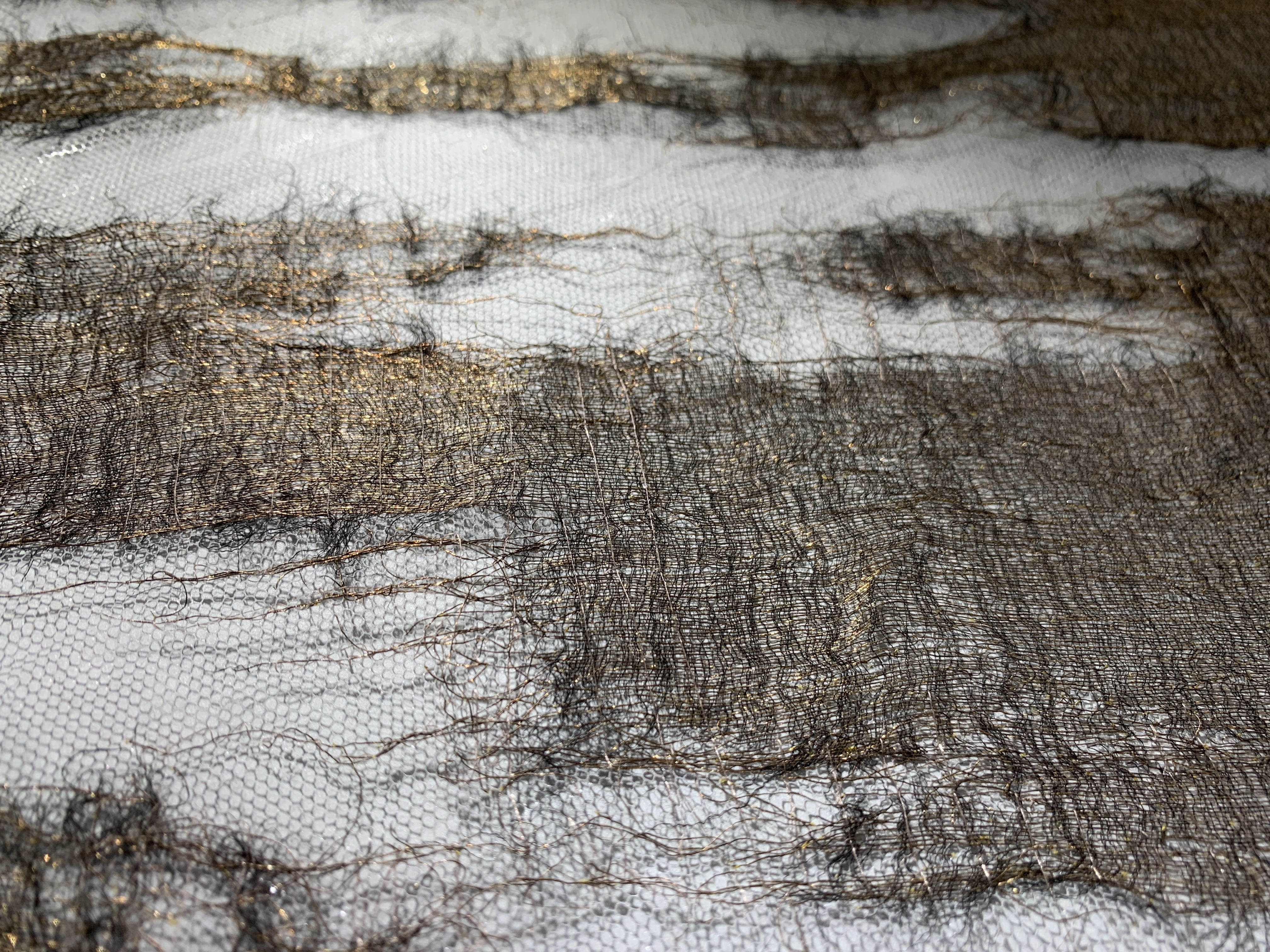 A close-up of a partially torn and fragmented piece of golden fabric
