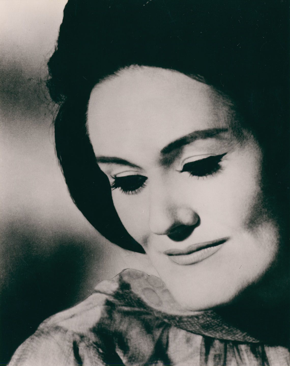 A black and white photographic portrait of Joan Sutherland, a slight smile on her face and eyes partly closed.