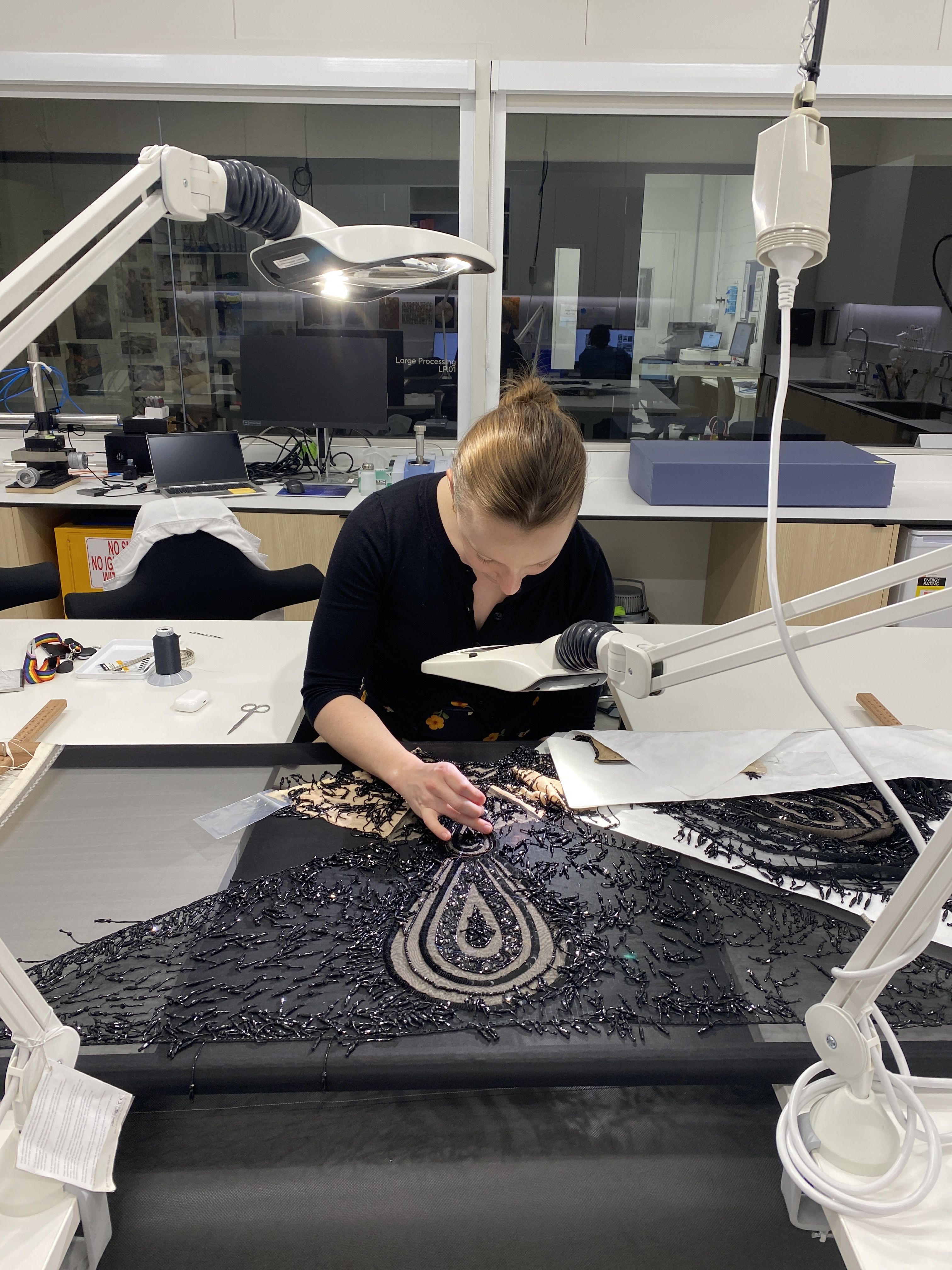 A conservator at work on the Merry Widow dress in a conservation lab