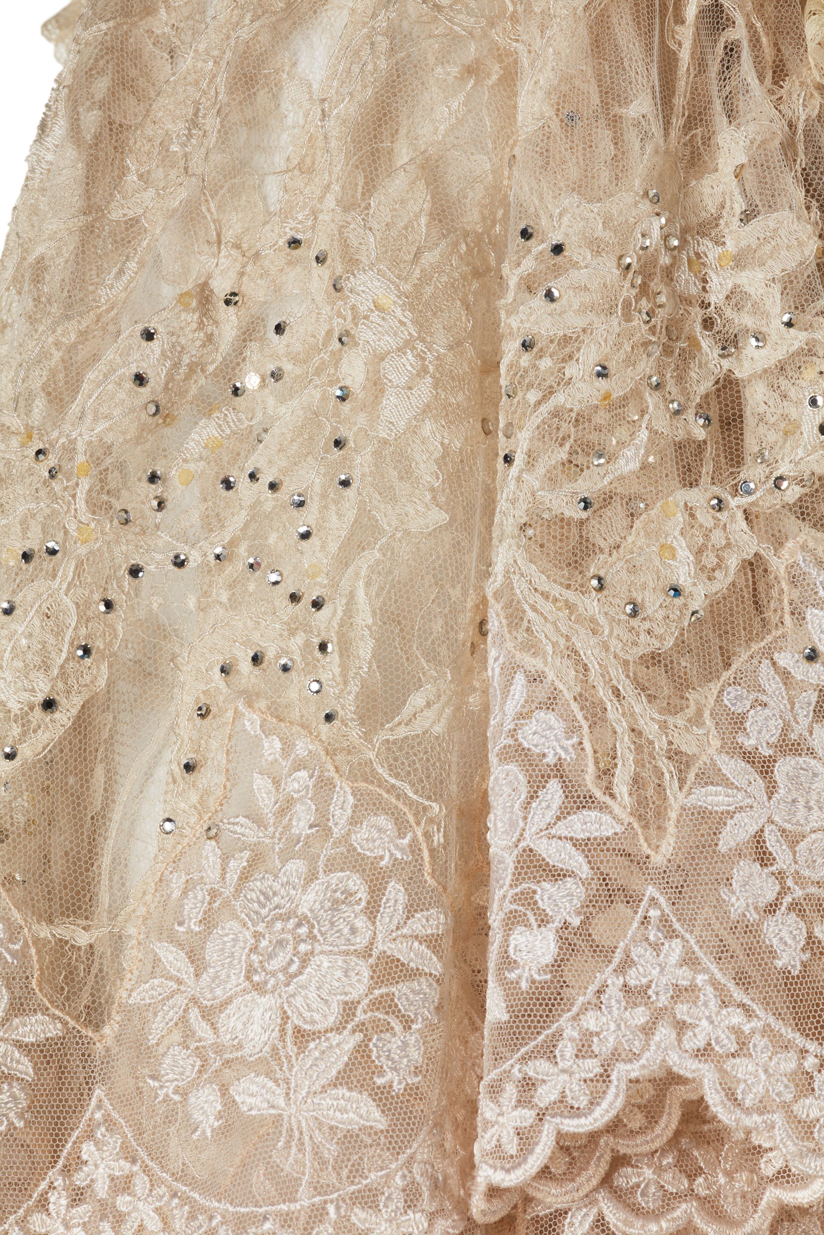 A close-up of the white lace sleeve of the costume, dotted with sequins