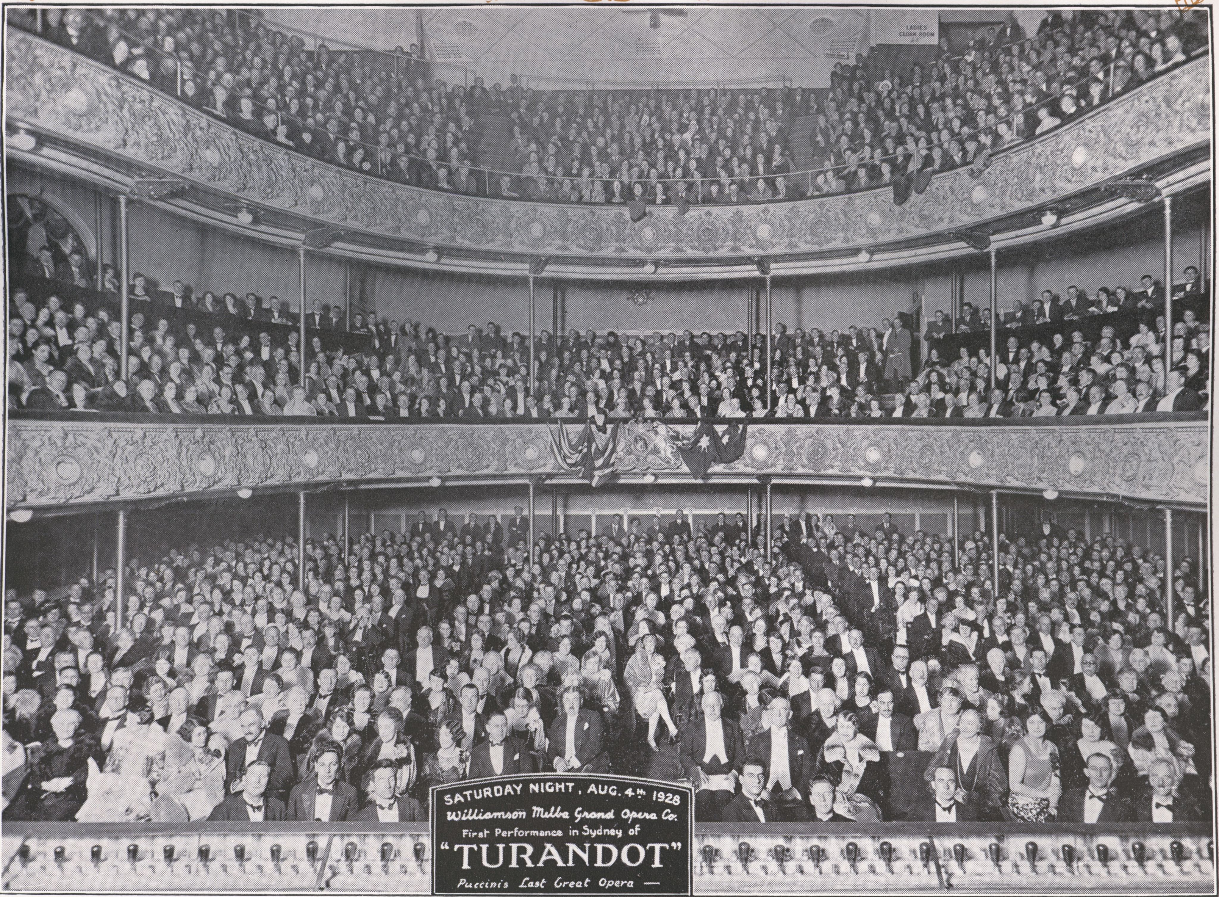 Photograph of audience in a theatre. Three tiers of a packed theatre. 
