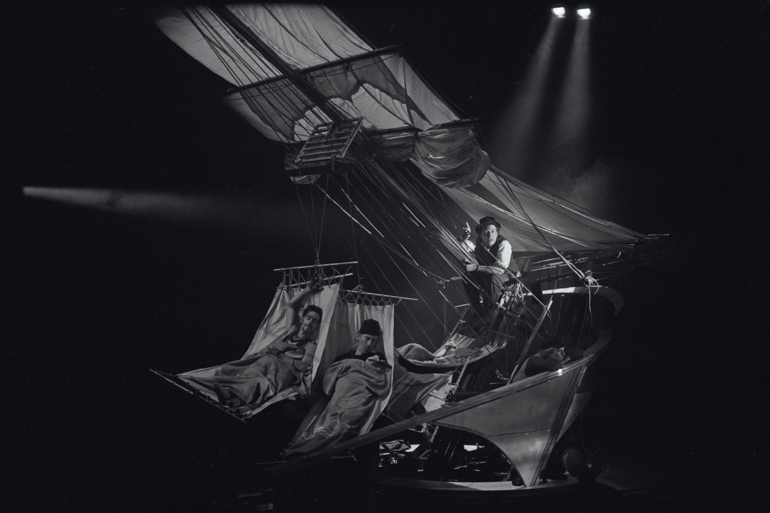 Theatre set that features a 19th century ship. Actors lay in hammocks on board the ship.