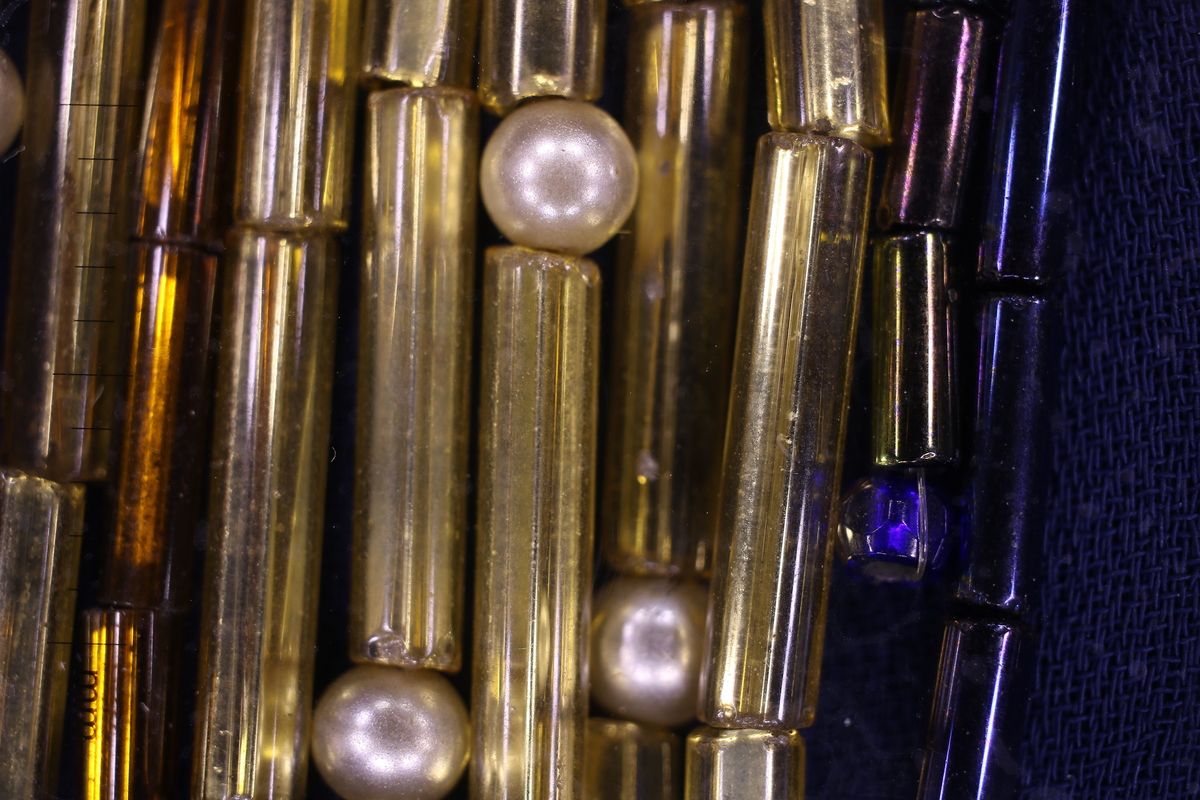 Macro photograph showing detail of gold bugle bead strands over blue silk chiffon gown from The Tales of Hoffmann