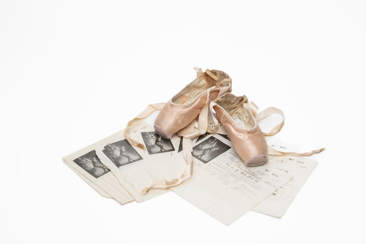 Colour image of ballet shoes resting on fanned our pieces of paper.