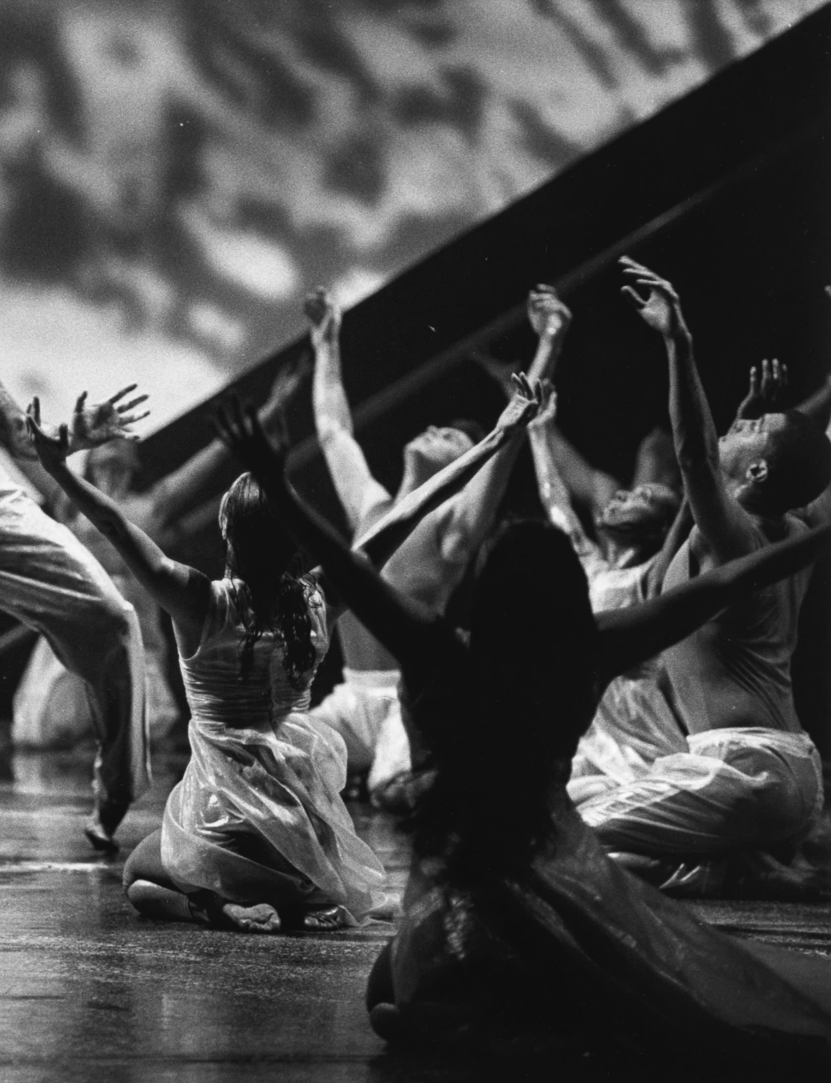 Dancers are seated with arms raised in a V shape.