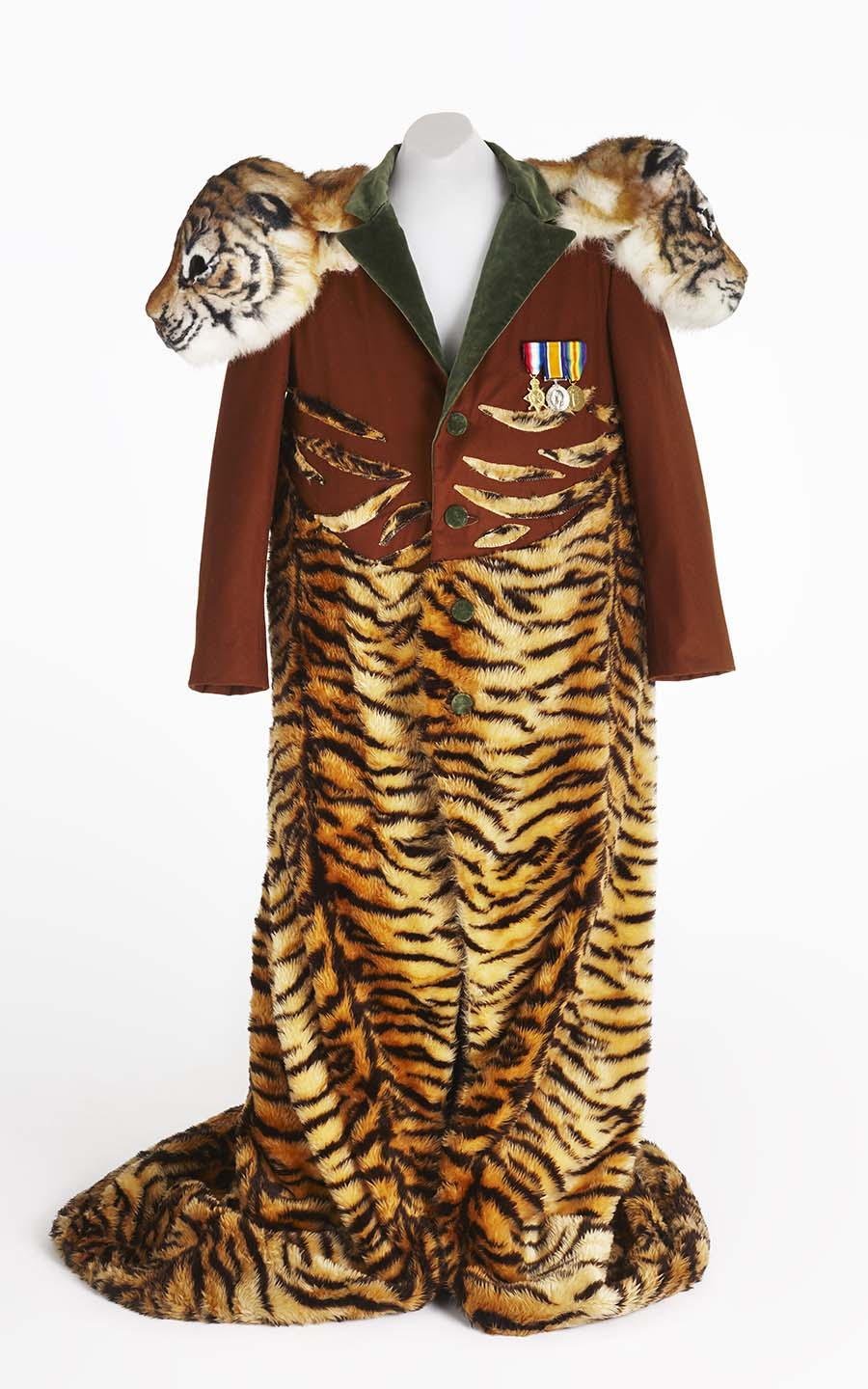 Theatrical costume on white mannequin. Features a brown coat with green lapel and buttons, and three medals. Faux-fur tiger material features from mid to end length. Each shoulder features a 3D prop tigers head.