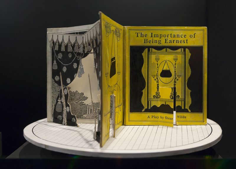 A cardboard set model on a circular stage, designed to resemble a large open book.