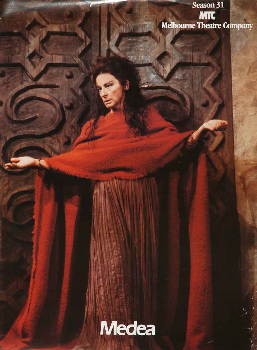 A woman in woollen shawl and dress standing outside the carved wooden door of a Greek temple.